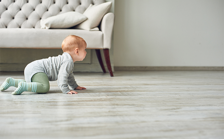 baby on linoleum floors with a couch in the background